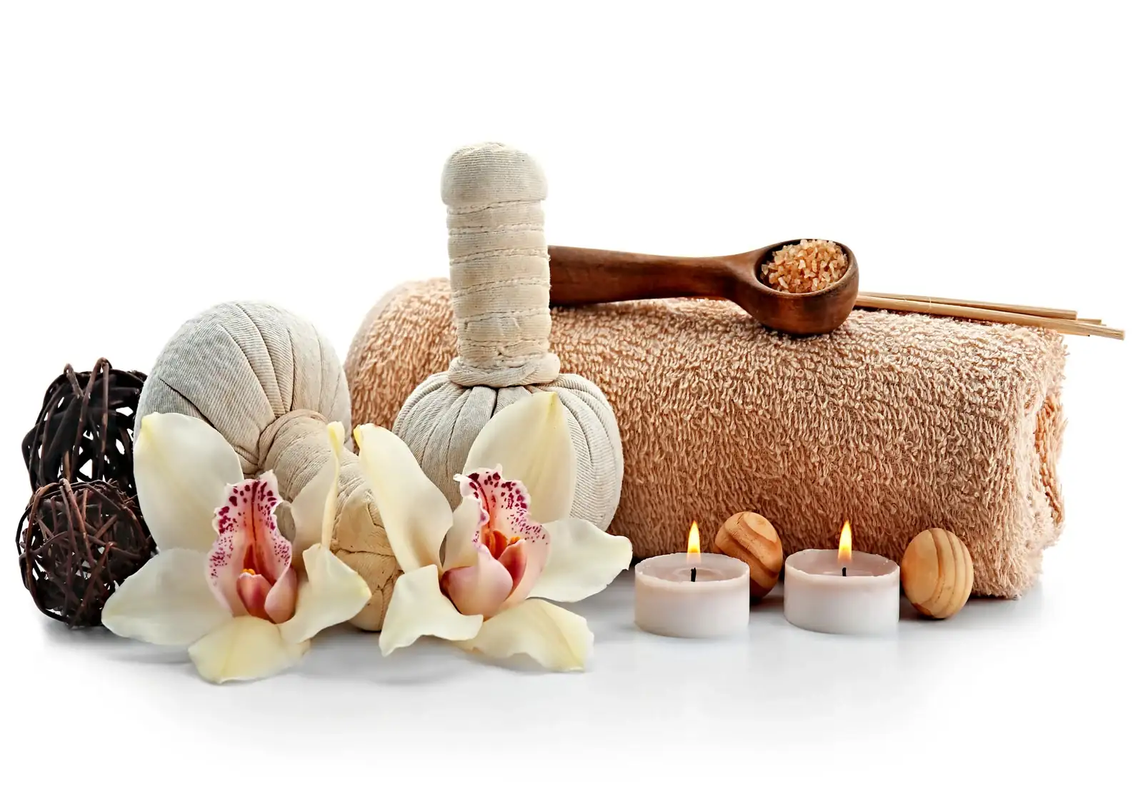 Herbal compress massage balls, candles, and a rolled-up towel on a wooden surface, representing a professional massage therapy setup.