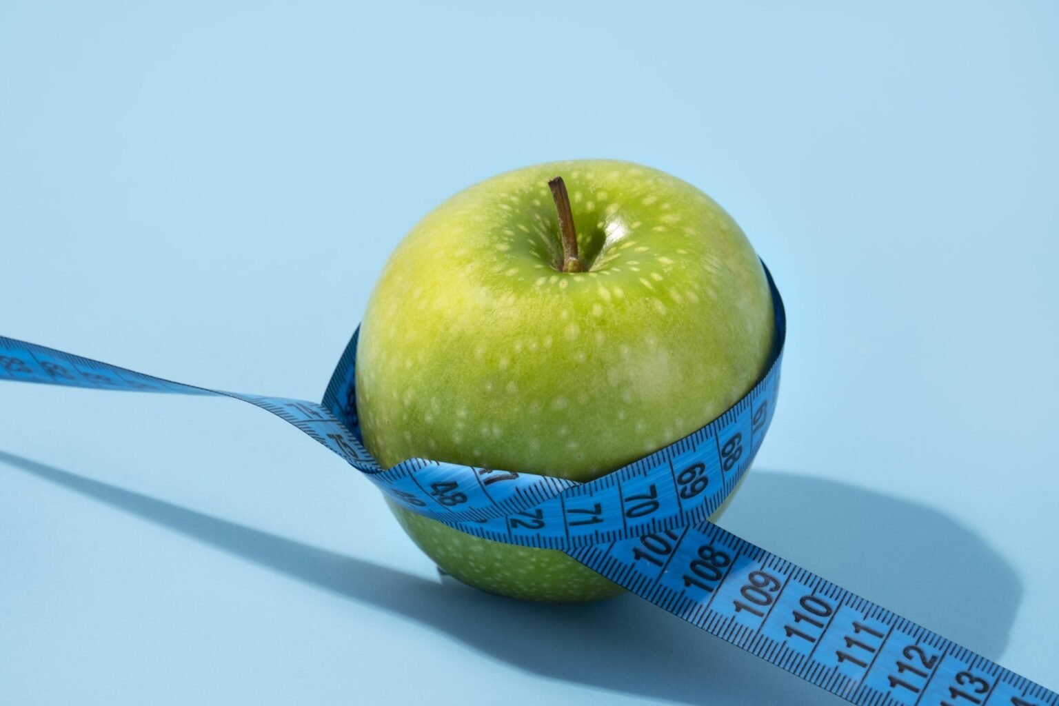 Measuring tape and fresh apple, symbols of a balanced weight loss plan